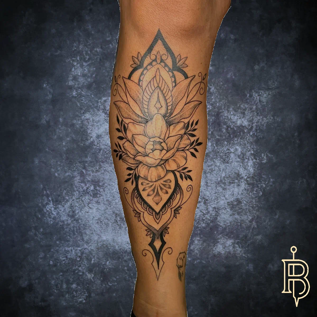 Längliches Bein-Tattoo: große Lotusblüte mit Mandala-Ornamenten und feinen Blattmustern, schwarzgrau.